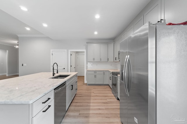 kitchen with backsplash, a center island with sink, sink, light hardwood / wood-style flooring, and appliances with stainless steel finishes