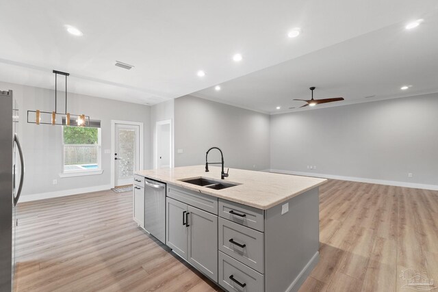 kitchen with stainless steel appliances, light hardwood / wood-style floors, a center island with sink, and sink