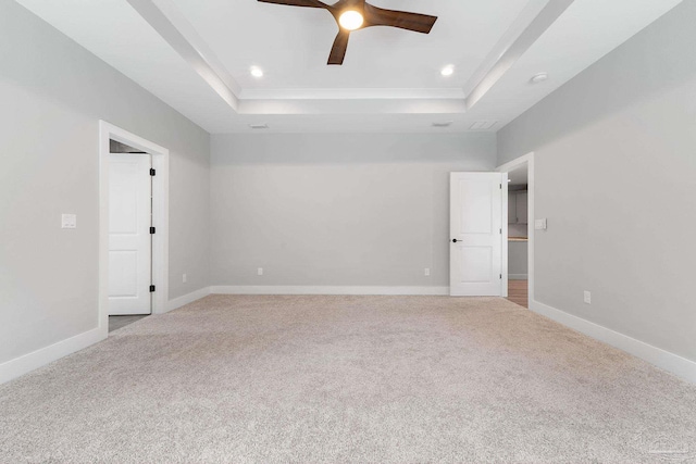 unfurnished room featuring ceiling fan, light carpet, and a tray ceiling