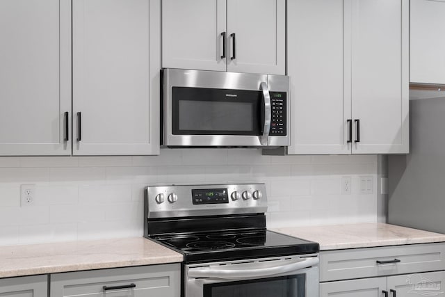 kitchen featuring light stone countertops, backsplash, and appliances with stainless steel finishes