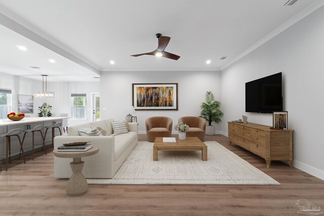 living room with ceiling fan with notable chandelier, light hardwood / wood-style floors, crown molding, and a wealth of natural light