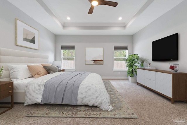 carpeted bedroom with ceiling fan, a tray ceiling, and multiple windows