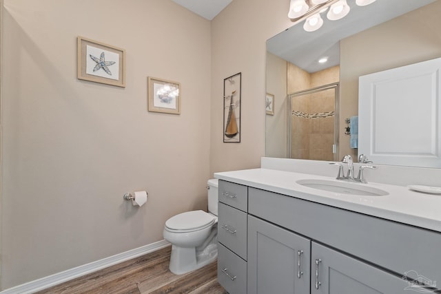 bathroom featuring hardwood / wood-style floors, vanity, toilet, and a shower with shower door