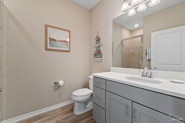 bathroom featuring wood-type flooring, vanity, toilet, and a shower with door