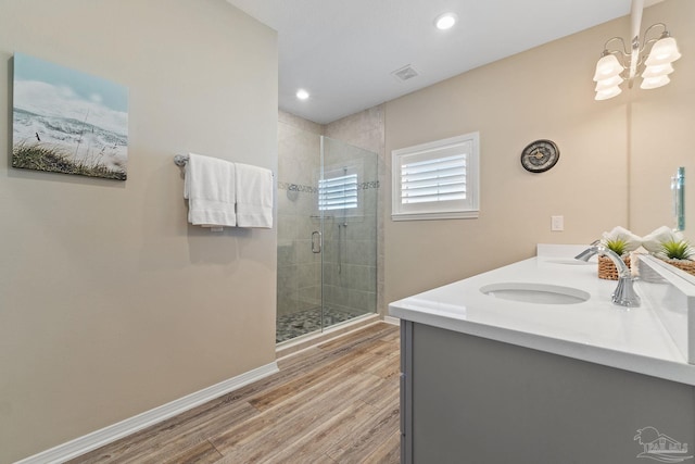 bathroom with a notable chandelier, vanity, wood-type flooring, and a shower with door