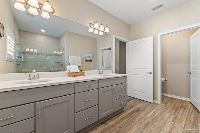 bathroom with hardwood / wood-style floors, vanity, and a shower with door