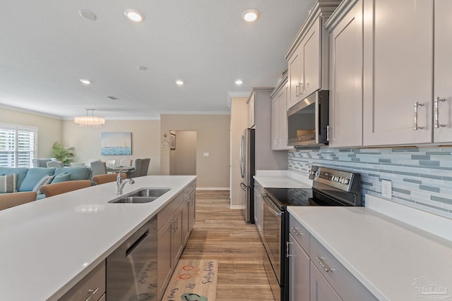 kitchen featuring gray cabinetry, sink, light hardwood / wood-style flooring, appliances with stainless steel finishes, and tasteful backsplash