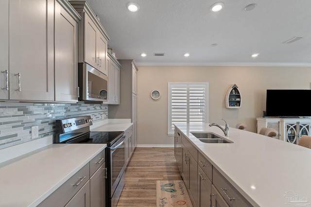 kitchen with sink, decorative backsplash, gray cabinets, appliances with stainless steel finishes, and light hardwood / wood-style floors