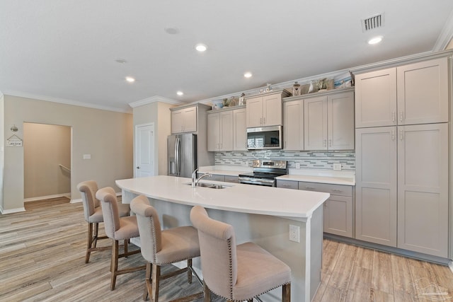 kitchen with sink, crown molding, gray cabinets, appliances with stainless steel finishes, and light wood-type flooring