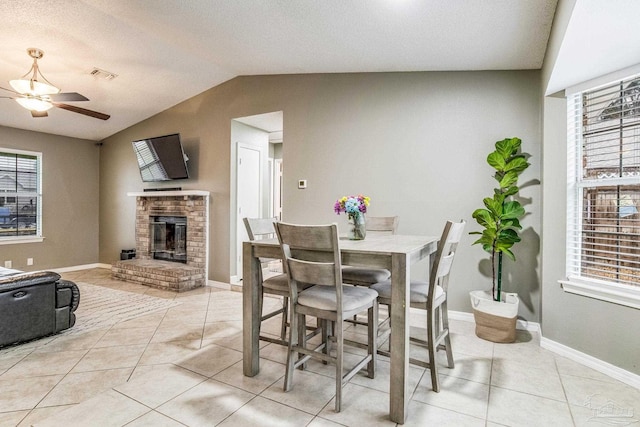 dining space with vaulted ceiling, light tile patterned floors, a wealth of natural light, and a fireplace