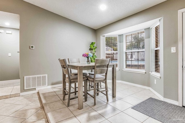 dining area featuring a textured ceiling and light tile patterned floors