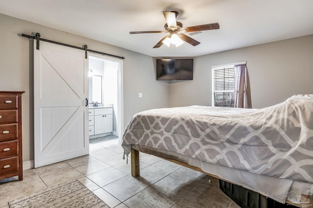 tiled bedroom featuring ceiling fan, connected bathroom, and a barn door