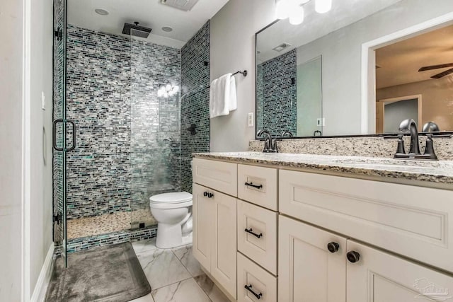 bathroom featuring toilet, ceiling fan, a shower with shower door, and vanity