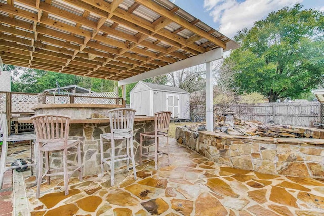 view of patio with an outdoor bar and a storage unit