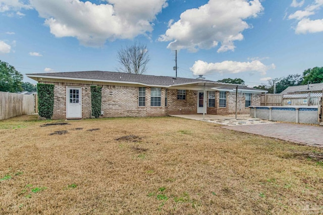 back of property with a fenced in pool, a yard, and a patio