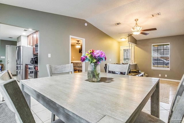 tiled dining area with a textured ceiling and vaulted ceiling