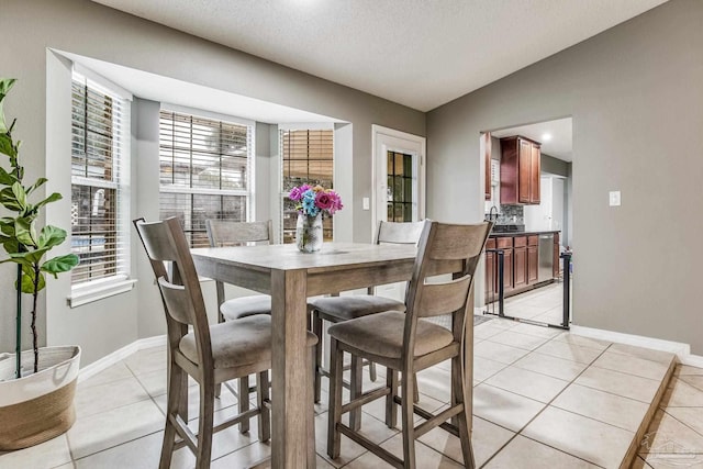 dining room with vaulted ceiling, plenty of natural light, and light tile patterned flooring