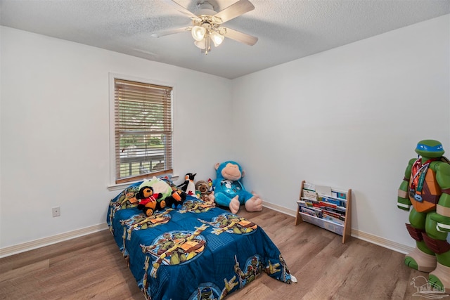 bedroom with ceiling fan, light hardwood / wood-style floors, and a textured ceiling