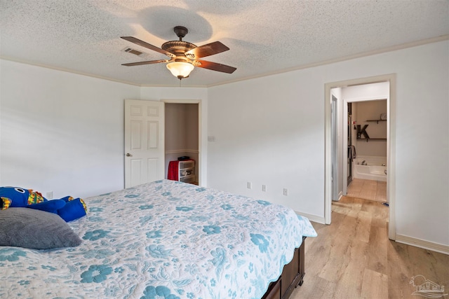 bedroom with a textured ceiling, ceiling fan, light wood-type flooring, and ensuite bathroom