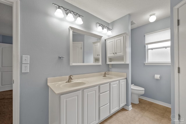 bathroom featuring tile patterned flooring, a textured ceiling, toilet, and dual bowl vanity