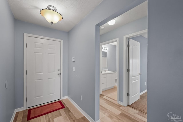 entryway with sink, a textured ceiling, and light hardwood / wood-style floors