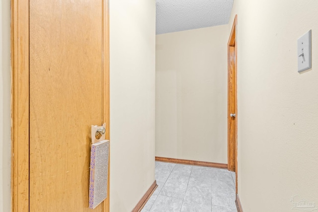 hall featuring a textured ceiling and light tile patterned floors