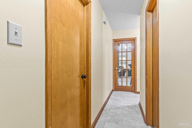 corridor with light tile patterned flooring and a textured ceiling