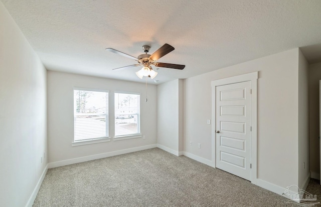 spare room with a textured ceiling, carpet floors, ceiling fan, and baseboards