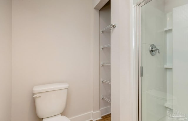 full bath featuring toilet, a stall shower, and baseboards