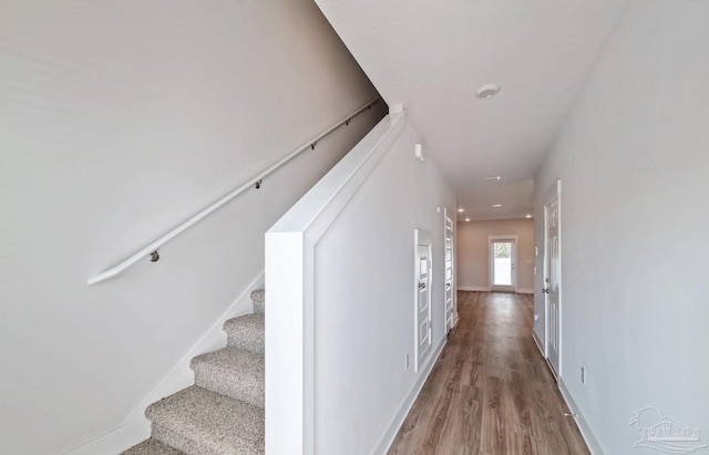 corridor with stairs, baseboards, and wood finished floors