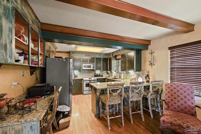 kitchen featuring light hardwood / wood-style floors, tasteful backsplash, kitchen peninsula, stainless steel appliances, and light stone countertops