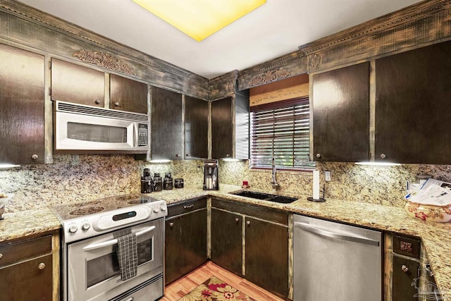 kitchen featuring light stone countertops, stainless steel appliances, light hardwood / wood-style flooring, dark brown cabinetry, and sink