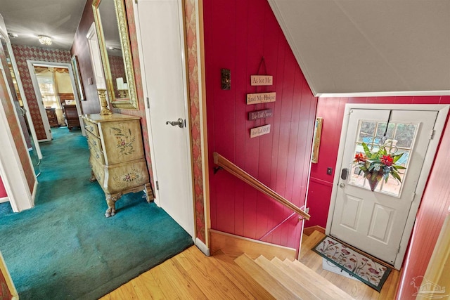 foyer entrance featuring lofted ceiling, wooden walls, and hardwood / wood-style floors