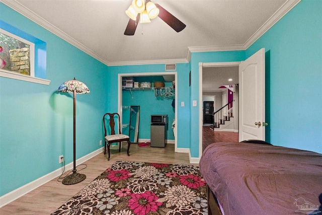 bedroom with a closet, ceiling fan, wood-type flooring, and crown molding