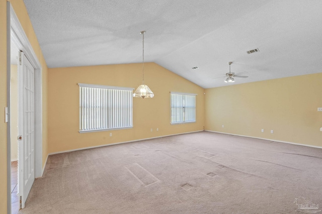 empty room featuring vaulted ceiling, light carpet, and ceiling fan with notable chandelier