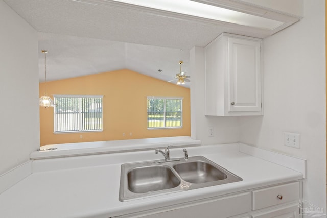 kitchen with lofted ceiling, sink, decorative light fixtures, white cabinetry, and ceiling fan