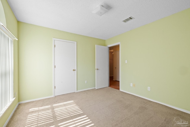 unfurnished bedroom featuring a textured ceiling and light colored carpet