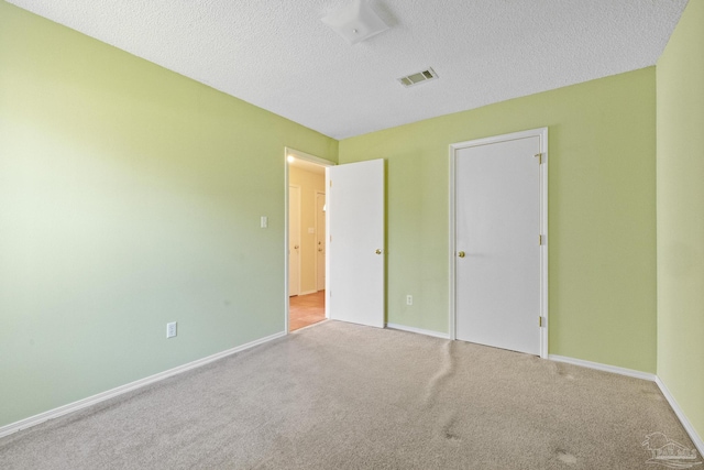 unfurnished bedroom featuring a textured ceiling and light colored carpet