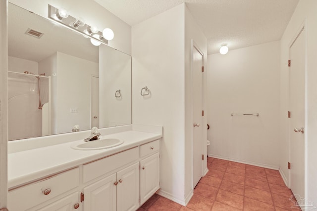 bathroom featuring vanity, a shower, tile patterned floors, and a textured ceiling