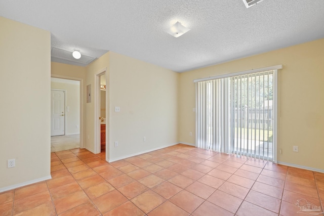 empty room featuring a textured ceiling and light tile patterned floors