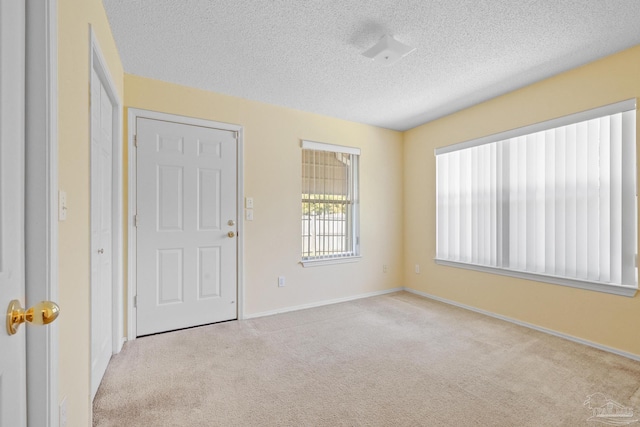 spare room with light carpet and a textured ceiling