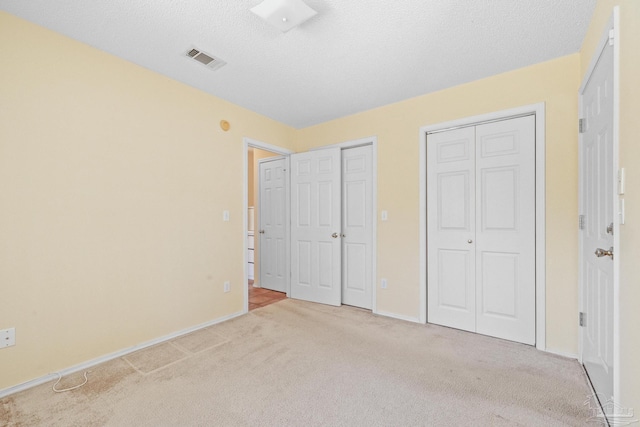 unfurnished bedroom featuring light carpet and a textured ceiling