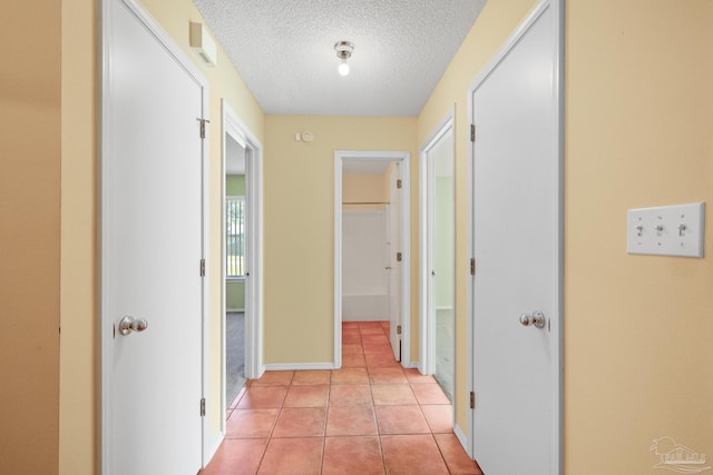 corridor with light tile patterned flooring and a textured ceiling