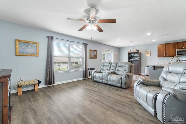 living room featuring recessed lighting, a ceiling fan, a textured ceiling, wood finished floors, and baseboards