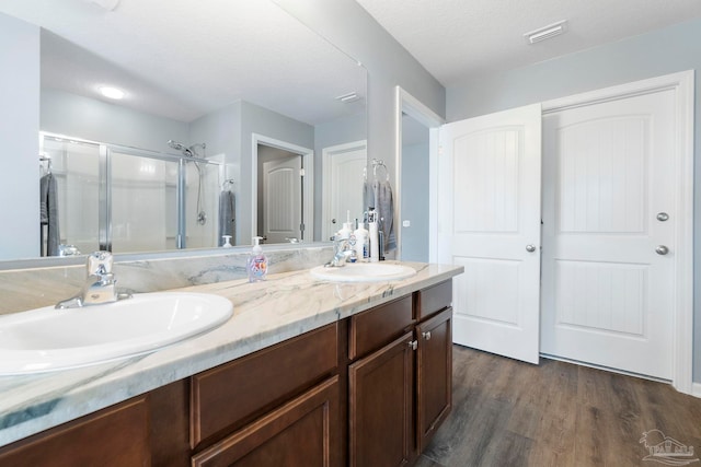 full bath featuring double vanity, a stall shower, a sink, and visible vents