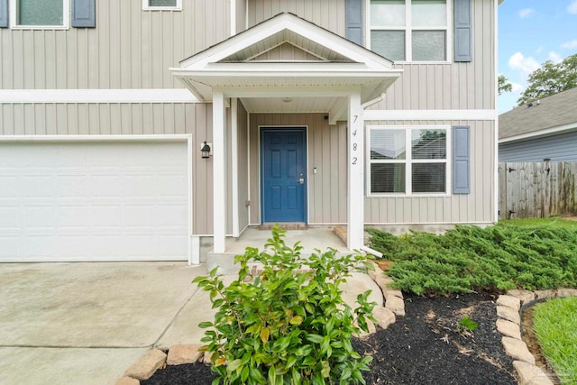 entrance to property with a garage, driveway, and fence