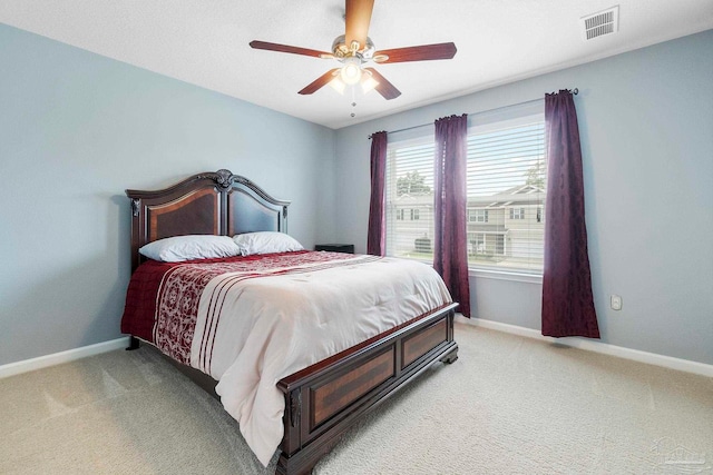 bedroom with light carpet, ceiling fan, visible vents, and baseboards