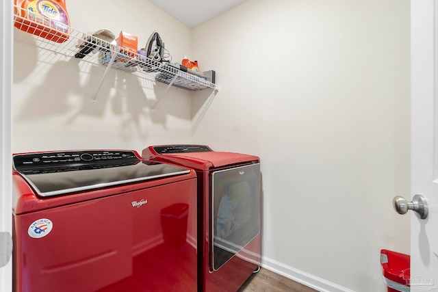 laundry area featuring laundry area, washing machine and dryer, baseboards, and wood finished floors