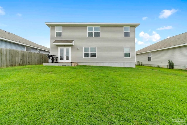 rear view of house with french doors, a fenced backyard, a yard, and a patio