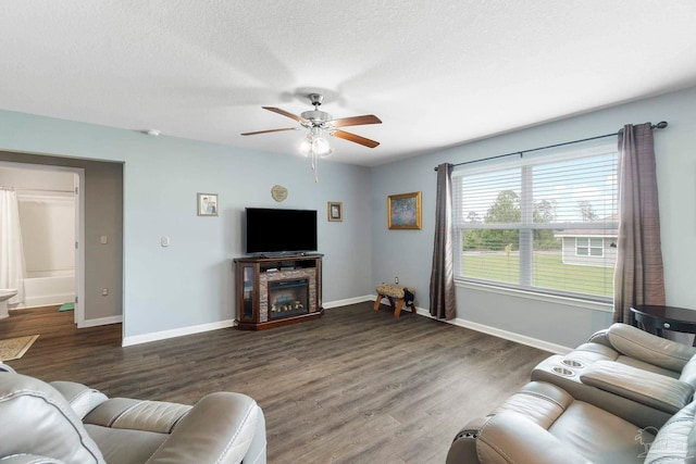 living room featuring baseboards, a ceiling fan, wood finished floors, a textured ceiling, and a fireplace